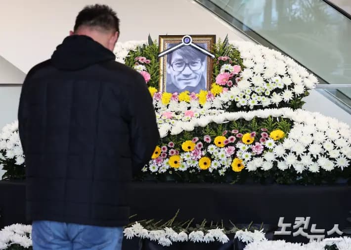 首尔电影中心故安圣基追思空间,吊唁者献花后默哀的场景